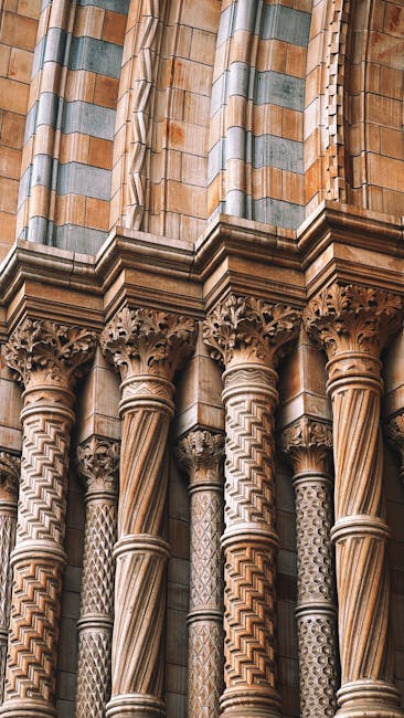 Close-up view of the highly detailed stone columns of a historic building located near the V and A Museum in South Kensington, showcasing intricate carvings and patterns on the capitals and shafts. The stone surfaces exhibit a combination of smooth and textured finishes, with some areas appearing slightly weathered but overall clean and well-maintained. The columns are illuminated by natural light, emphasizing the craftsmanship and architectural features. This image highlights the importance of surface cleaning and conservation in historic architecture, relevant to domestic and commercial cleaning services offered by southkensingtoncarpetcleaners.com, especially in maintaining the aesthetic and structural integrity of such sites.